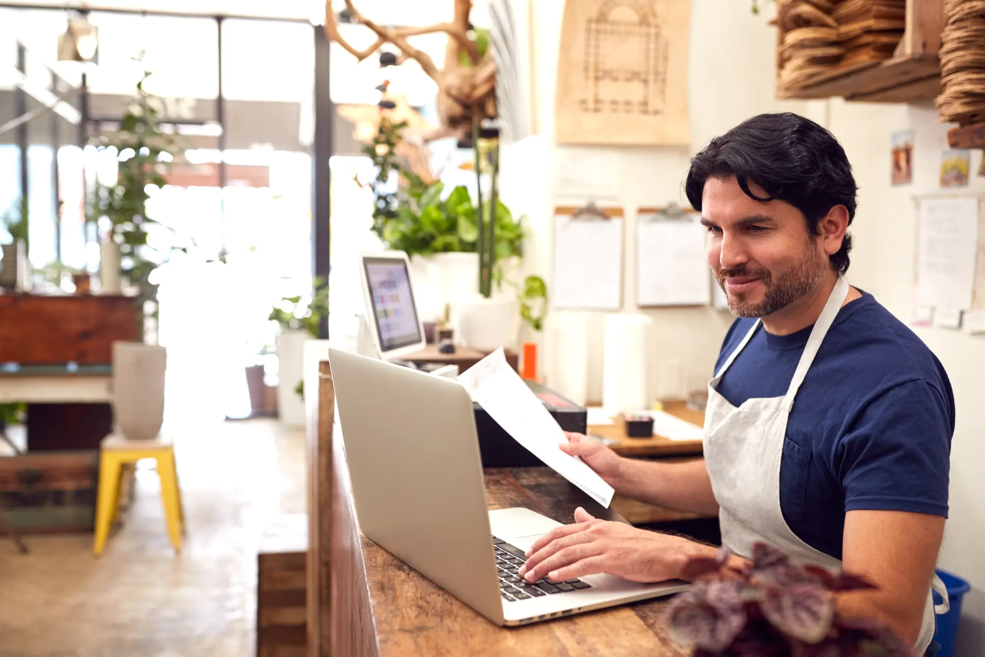البرامج 17 Male Sales Assistant Working On Laptop Behind Sales Desk Of Florists Store