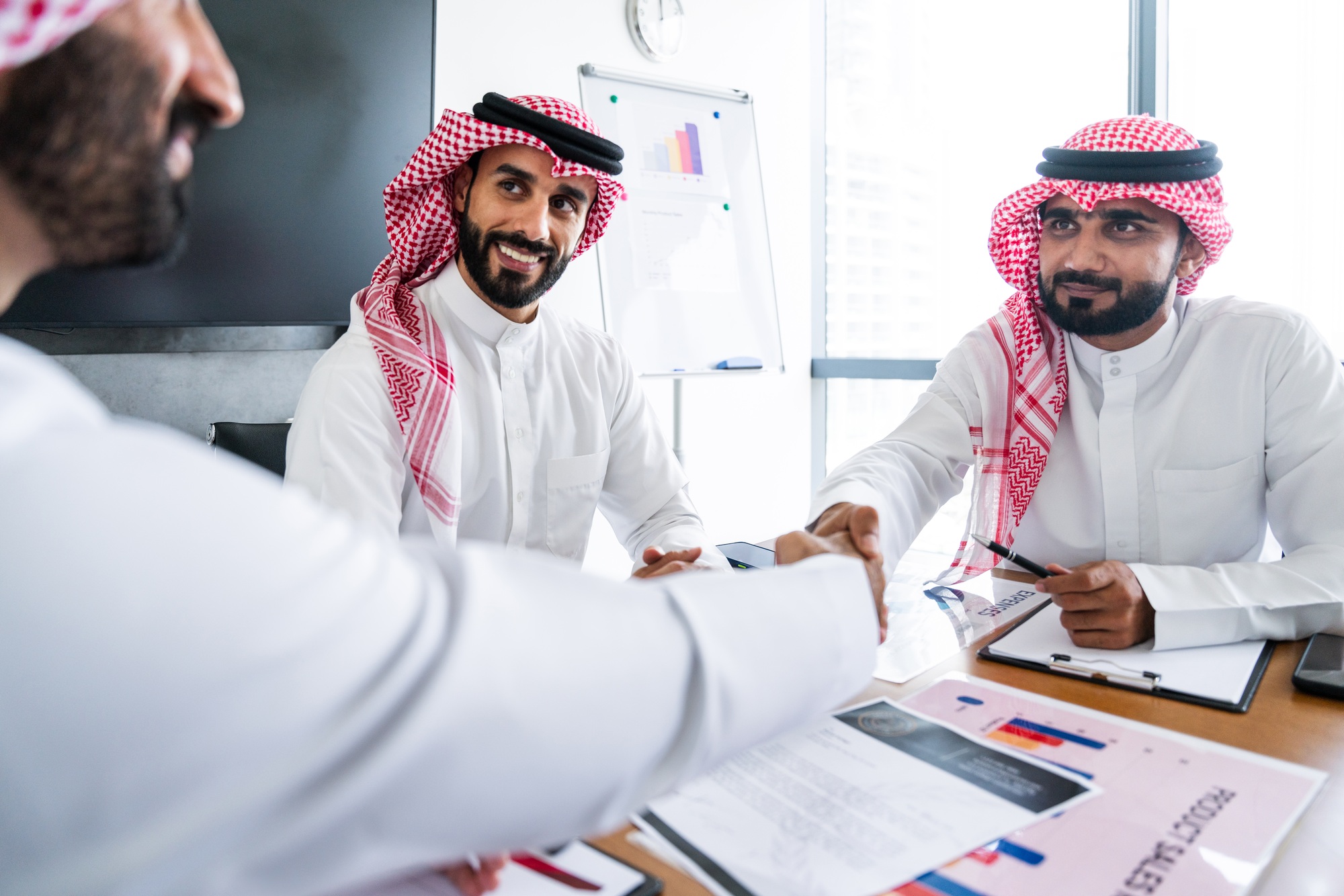 Arab businessmen wearing saudi kandura meeting in office for business deal