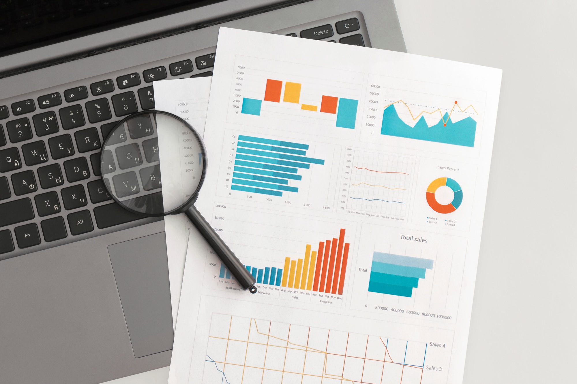 Business graphs, charts and magnifying glass on table. Financial development