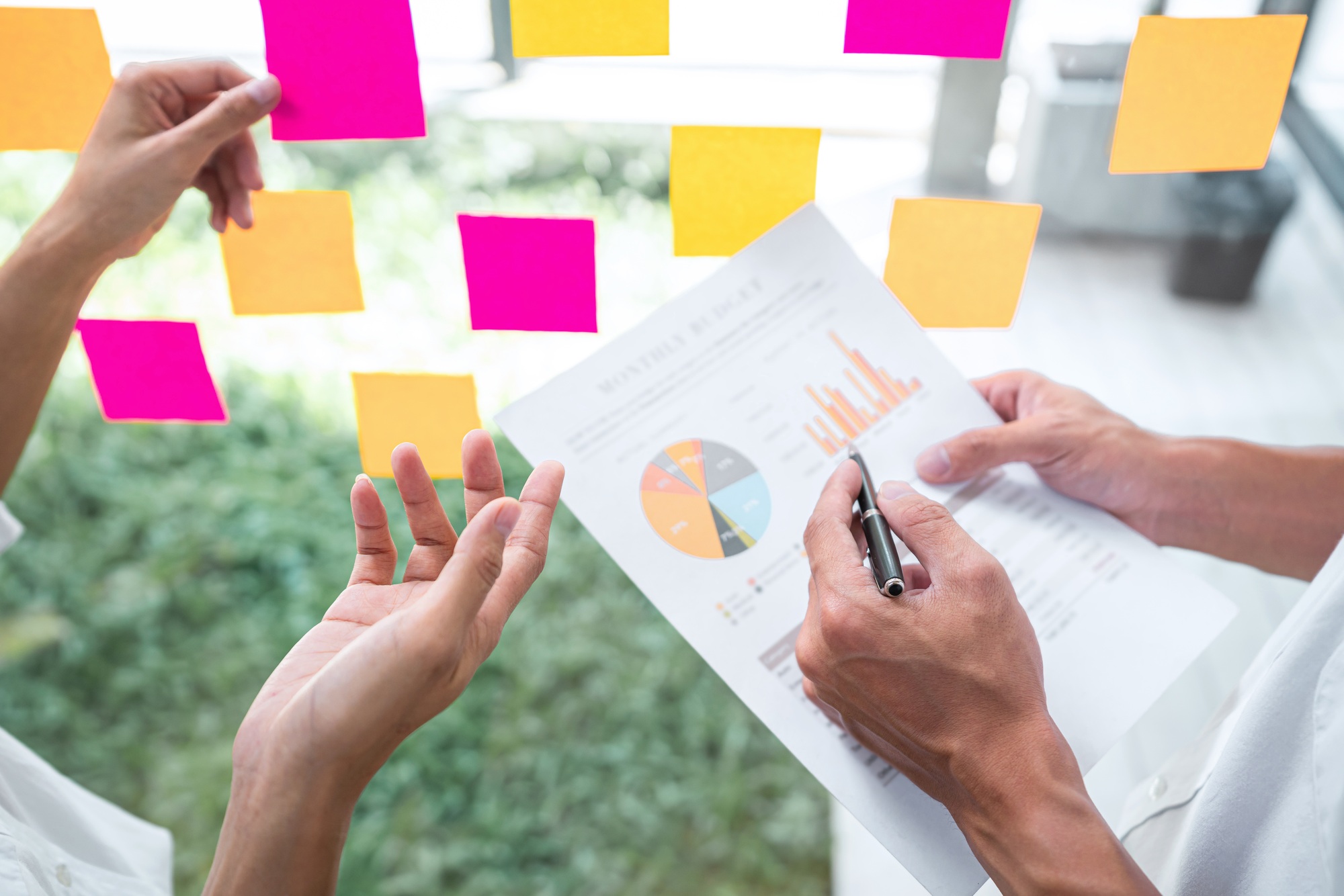Business team using post it notes in glass wall to writing strategy business plan to development