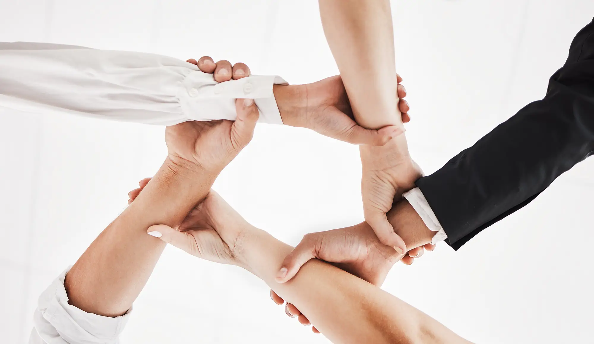 Low angle shot of a group of businesspeople holding one anothers wrists in a circular formation